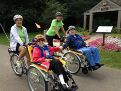 People ride specially designed bikes with a wheel chair in front.