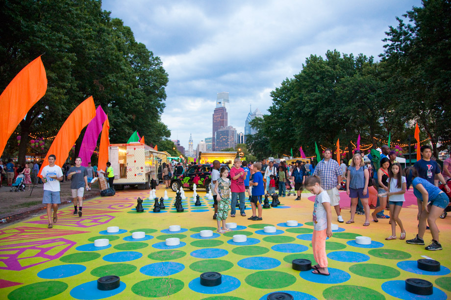 People play colorful giant checkers in a plaza.