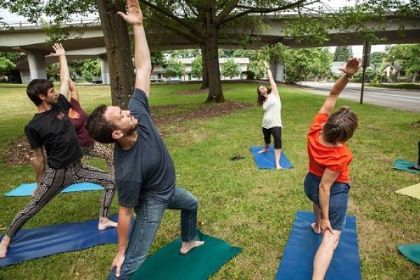 People do yoga in a park.