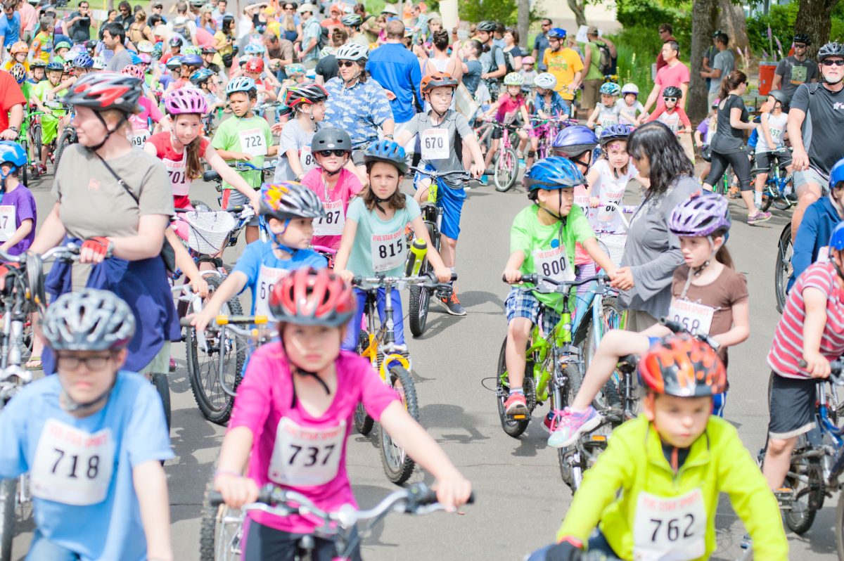 A large crowd of kids riding bikes down the street.