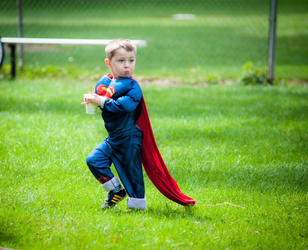 A child in a superman costume with a cape.