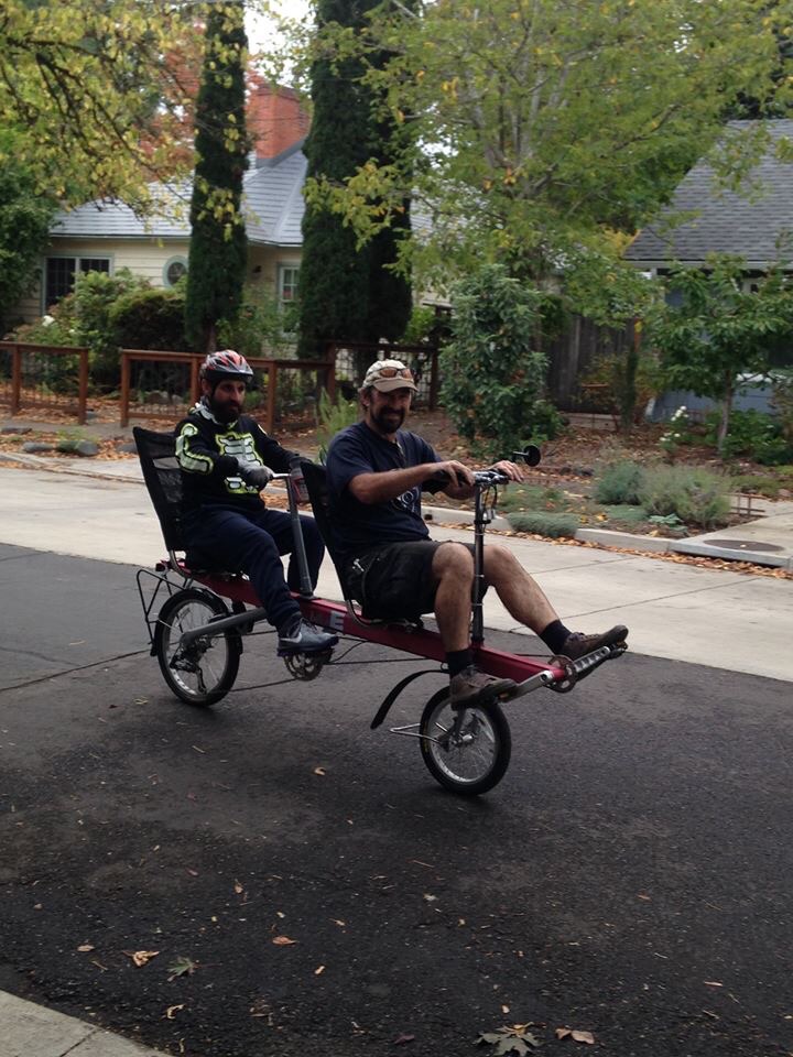 Two people ride a tandem recumbent bicycle