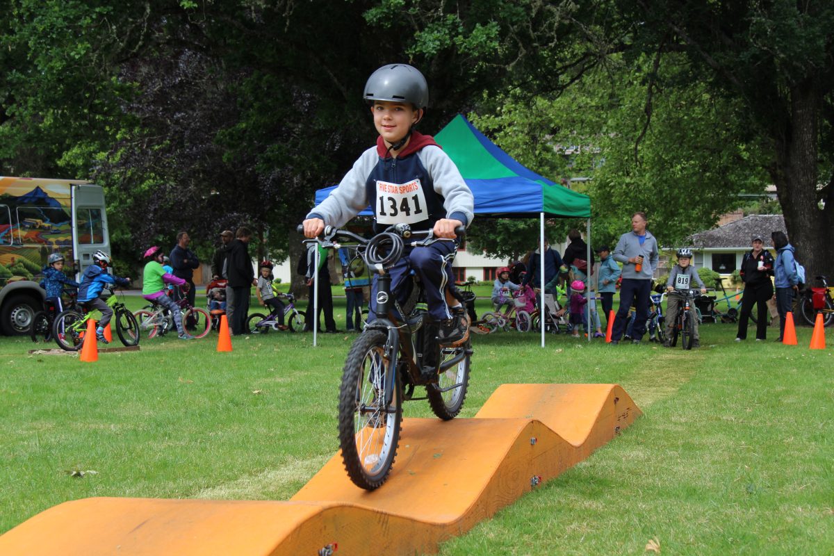 Child rides bike on wooden track.