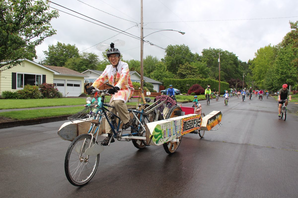 A person rides a large bicycle powered kinetic sculpture.