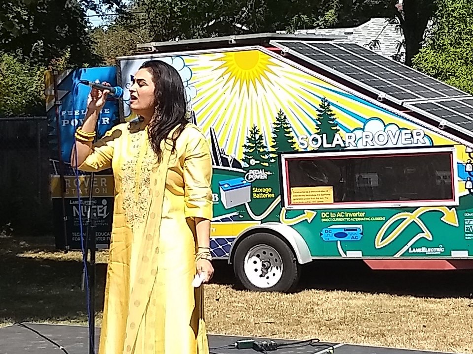 Person singing in front of solar trailer.