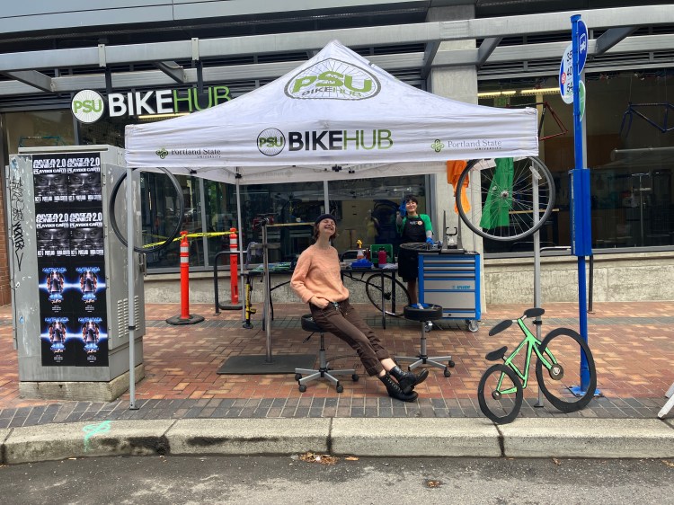 Bike mechanic sits under a canopy that says "Bike Hub"