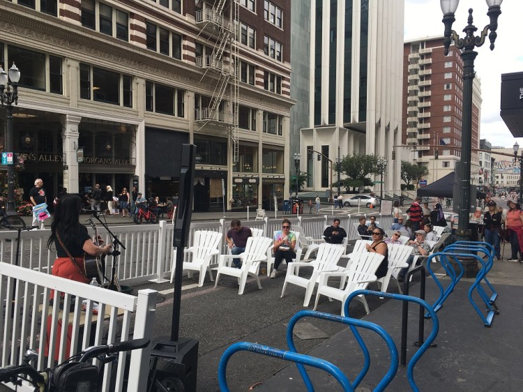 A singer performs in the street with a large seating area set up