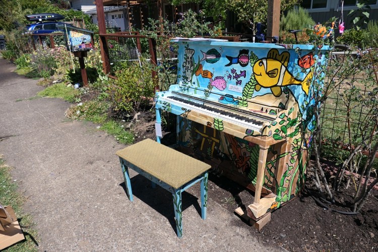 Painted upright paino sits along the sidewalk