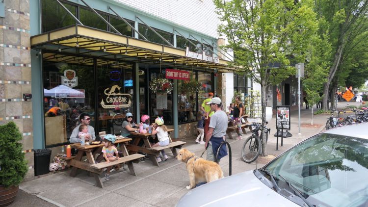 People sit on picnic tables in front of American Dream Pizza