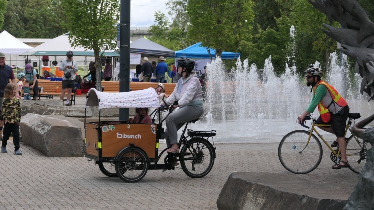 People bike in front of the fountain at Riverfront Park